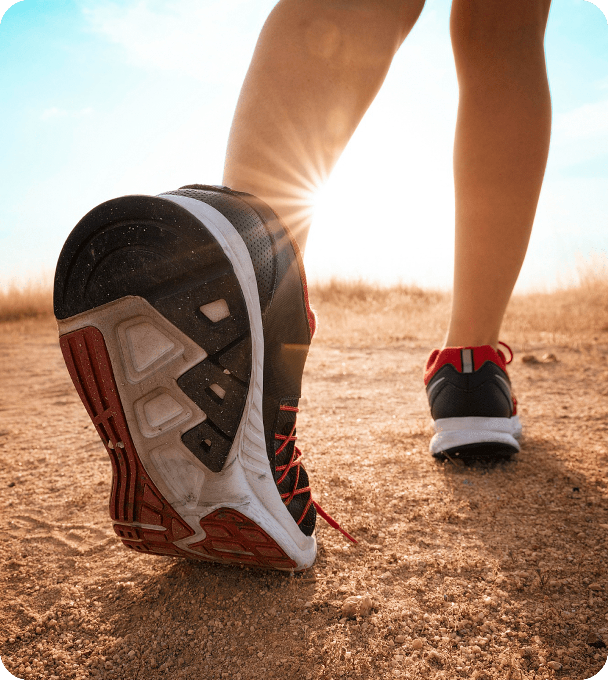 Running shoes on dirt path at sunset